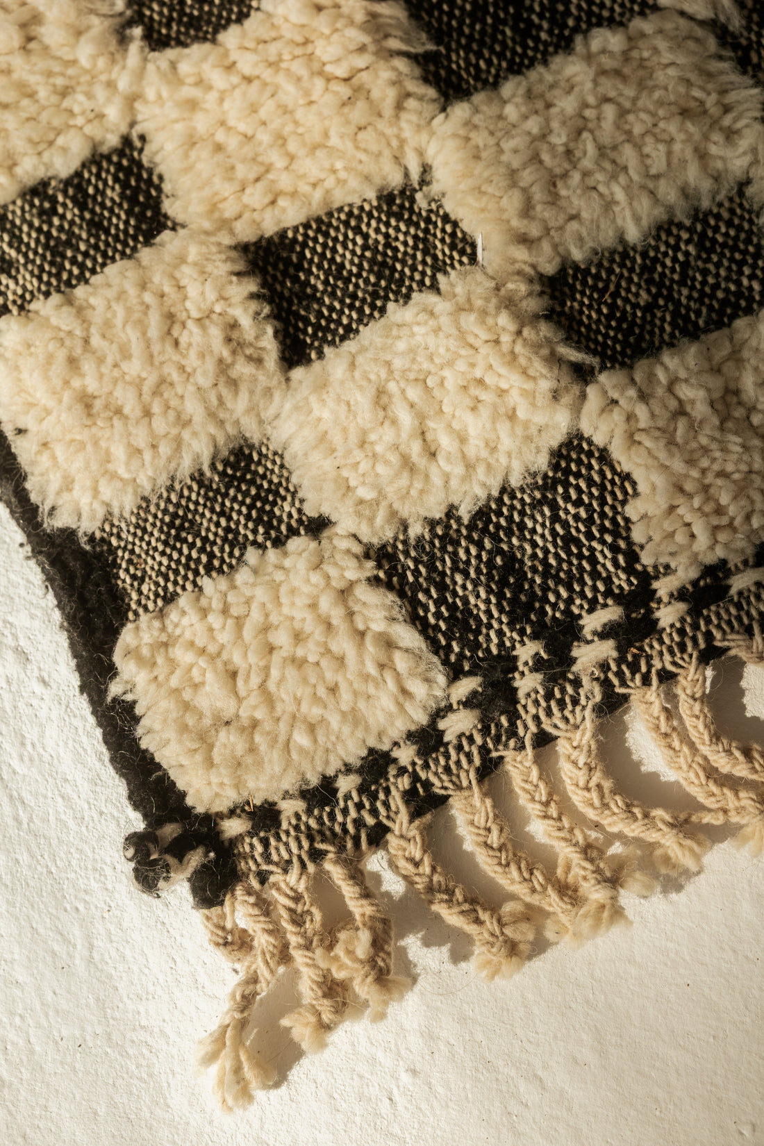 Close-up of a handwoven Berber wool rug showing thick pile texture and braided fringe